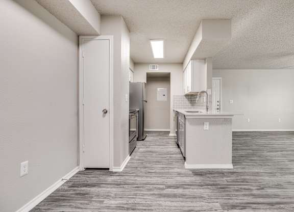 A kitchen area with a refrigerator, sink, and cabinets.