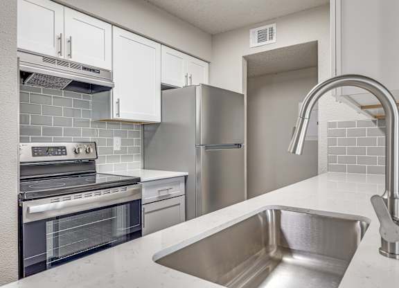A modern kitchen with a stainless steel sink and refrigerator.