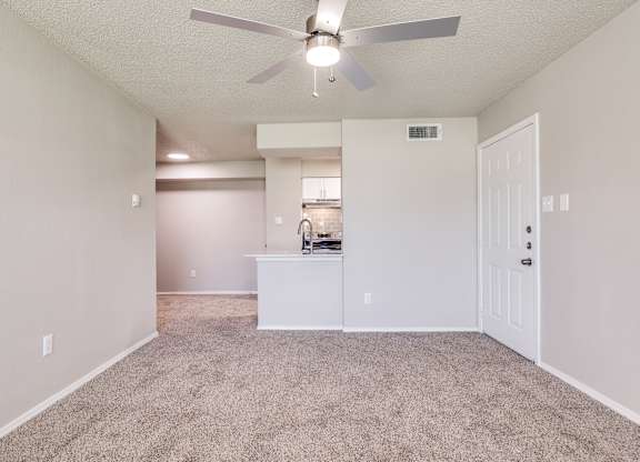 A spacious room with a ceiling fan and a carpeted floor.