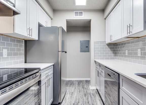 A modern kitchen with a stainless steel refrigerator and white cabinets.