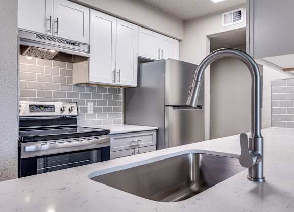 A modern kitchen with a stainless steel sink and refrigerator.