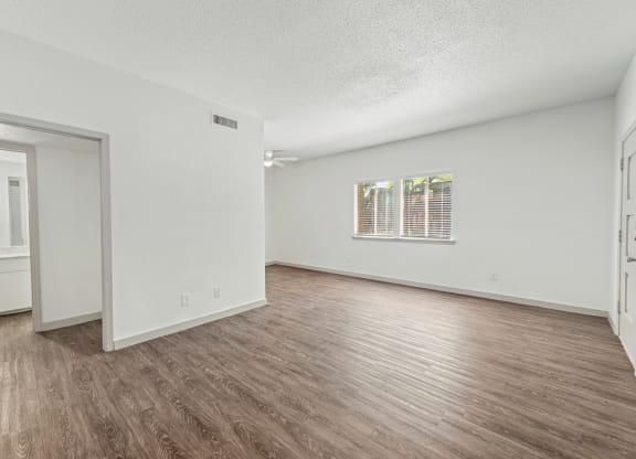 a spacious living room with white walls and wood flooring