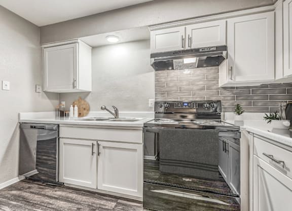 Updated kitchen with electric range and hood at Northwood Heights Apartments, Dallas, TX
