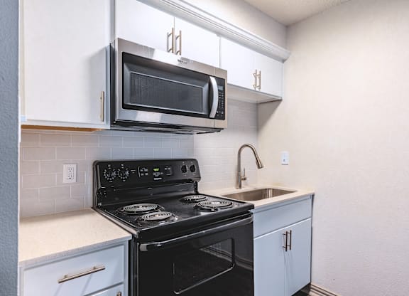 an empty kitchen with a stove and a sink and a microwave