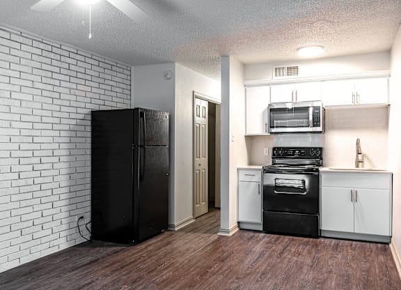 an empty kitchen with white appliances and a black refrigerator
