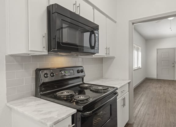 a kitchen with white cabinets and a black microwave and stove