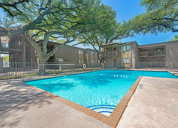 a swimming pool with trees and apartments in the background