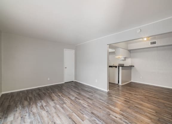 the living room of an apartment with wood flooring and a kitchen at Lumina, Texas