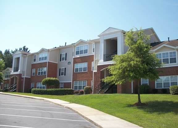 Apartment building with a parking lot in front.