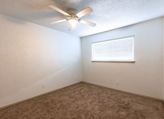 an empty room with a ceiling fan and a window