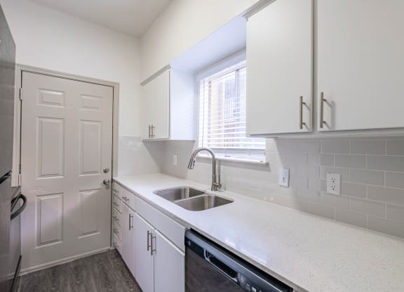 a kitchen with white cabinets and a sink and a window