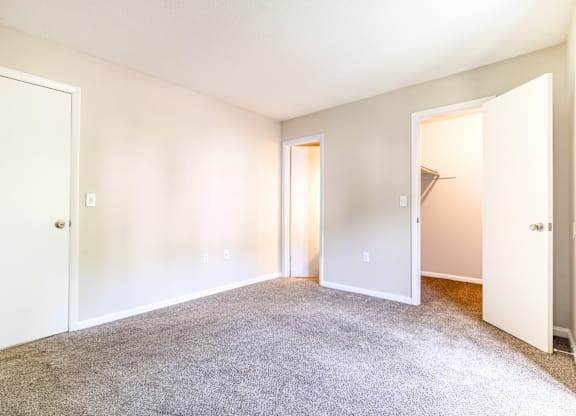 A large, empty room with carpeted floor and white walls.