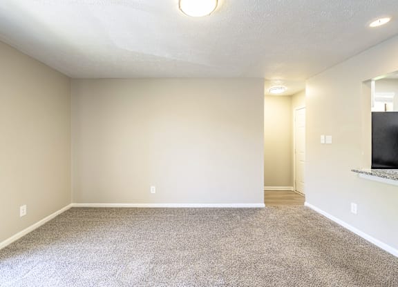 A sparsely furnished room with a carpeted floor and a window.