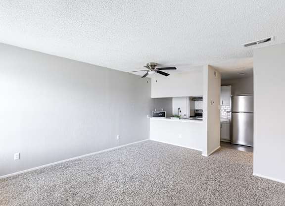 A spacious living room with a ceiling fan and a kitchen area in the background. at Leander, Texas, 76109