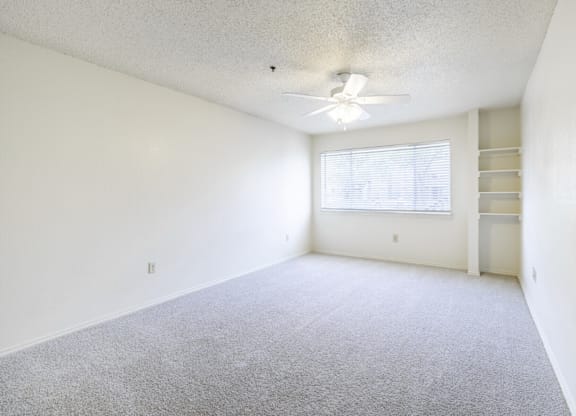 A room with a ceiling fan and a window with blinds.