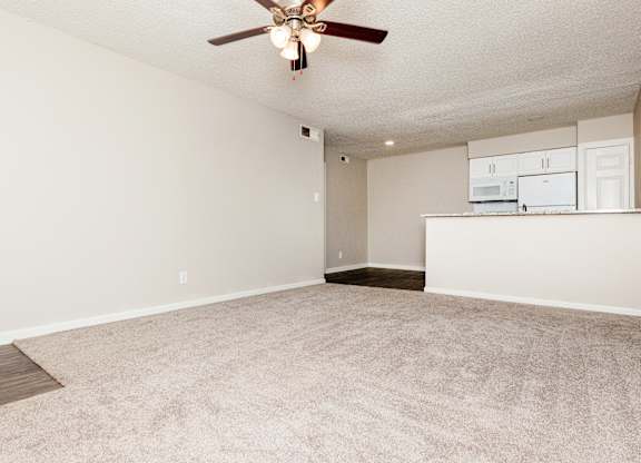 A room with a ceiling fan and carpeted floor.