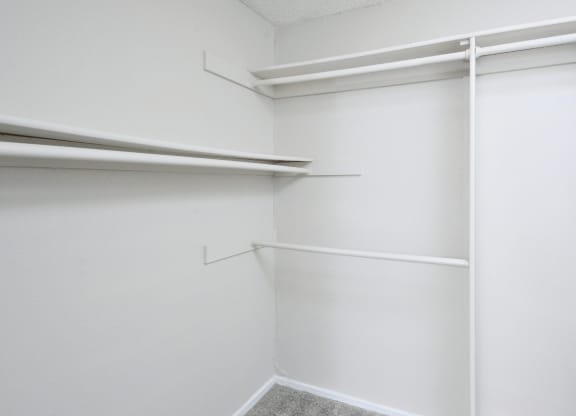 a walk in closet with white walls and white shelves and a white