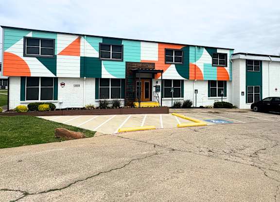 A white apartment building with a green, orange and blue design at Carisma in Richardson, TX.