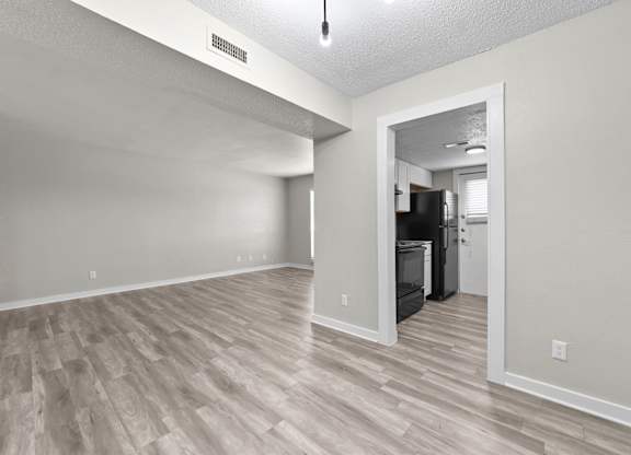 A kitchen area with a refrigerator and oven is visible through an open door.