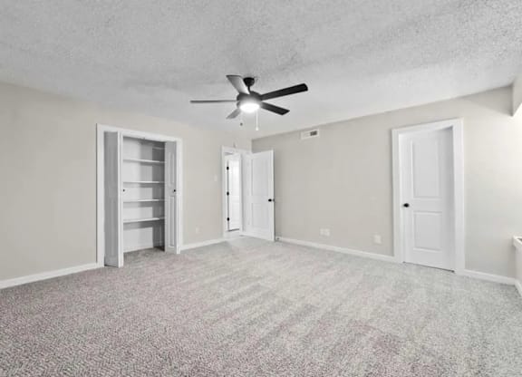 A room with a ceiling fan and carpeted floor.