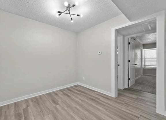 A room with a light grey wall and a light brown floor.
