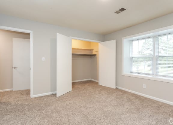 an empty bedroom with a closet and a window