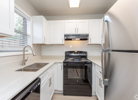a kitchen with white cabinets and black appliances and a stainless steel refrigerator
