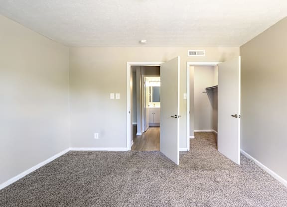 A room with carpeted floor and white walls with a doorway leading to another room.