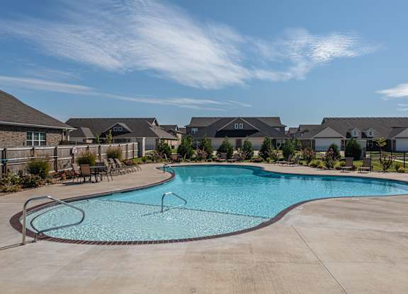 A large swimming pool in a residential area with houses in the background at Cedar Crest Apartments, Farmington, AR, 72730