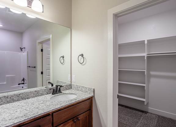 A bathroom with a sink, mirror, and a closet at Cedar Crest Apartments, Arkansas