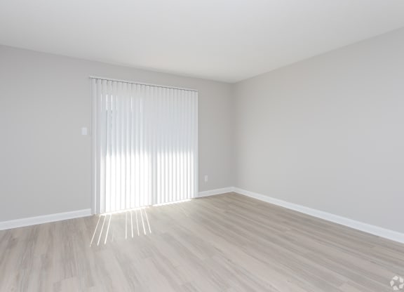 an empty room with white blinds and a window