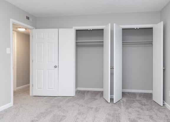 an empty bedroom with two closets and two doors