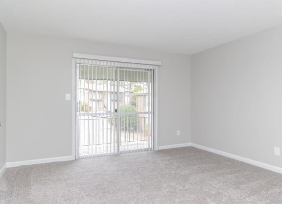 an empty living room with a sliding glass door to a patio