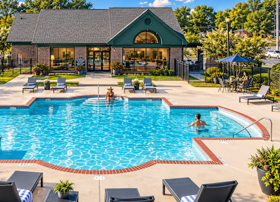 A large outdoor swimming pool with people in it and a building in the background.