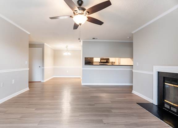 A living room with a fireplace and a ceiling fan. at Rosewood at Colony Square, Rocky Mount, 27804