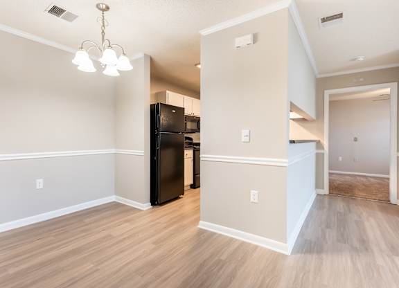 A kitchen area with a black fridge and wooden flooring. at Rosewood at Colony Square, Rocky Mount, NC