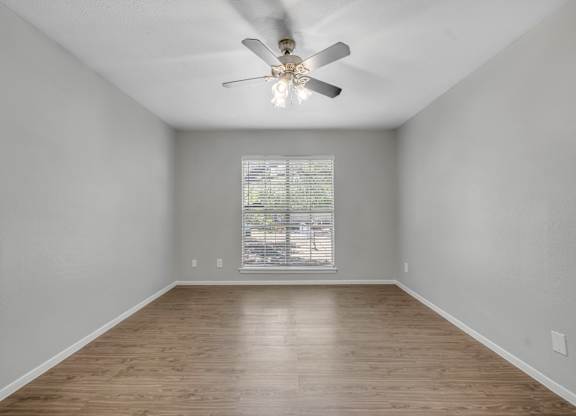 A room with a ceiling fan and wooden flooring.