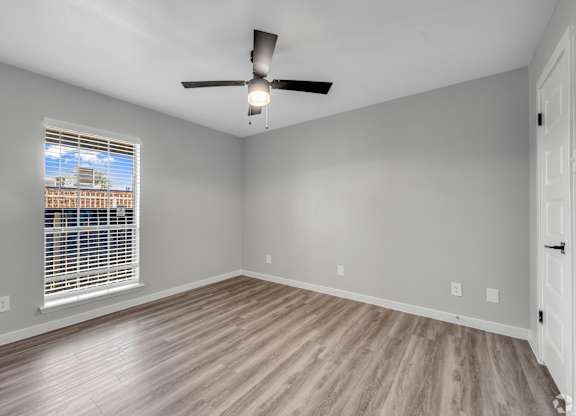 A room with a ceiling fan and a window with blinds.