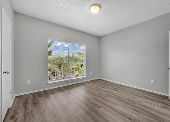 A room with a window and wooden flooring.