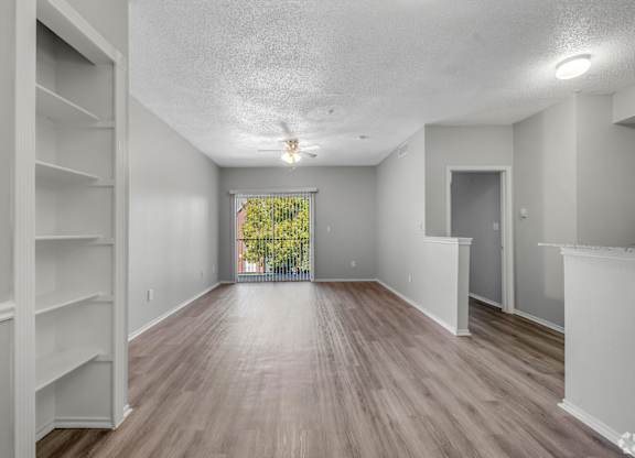 A spacious room with wooden flooring and white walls.