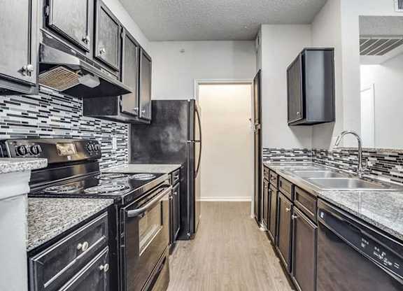 A kitchen with black appliances and a black fridge.
