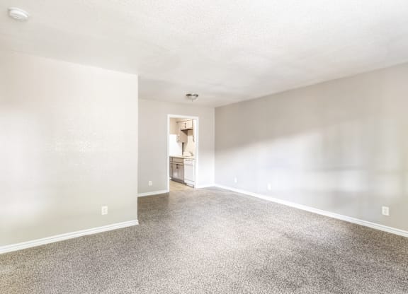 A spacious room with a carpeted floor and a doorway leading to another room.