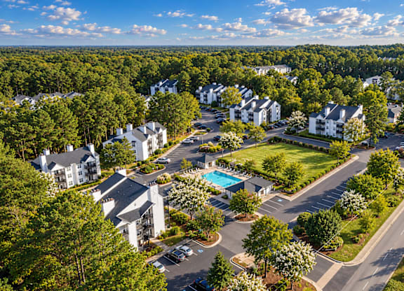A bird's eye view of a residential area with houses, roads, and a swimming pool.