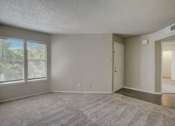 an empty living room with large windows and a door