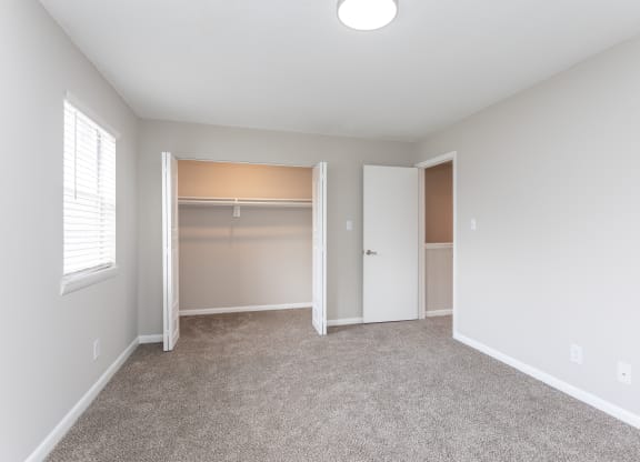 an empty room with a closet and a window