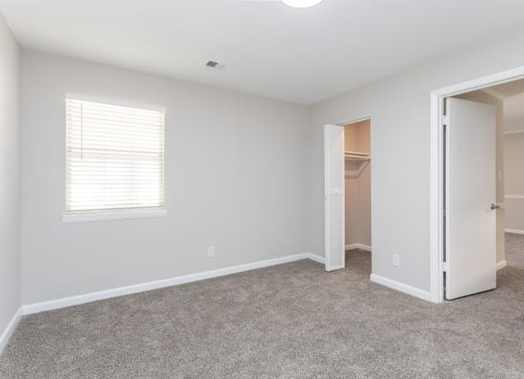 an empty bedroom with a closet and an open door