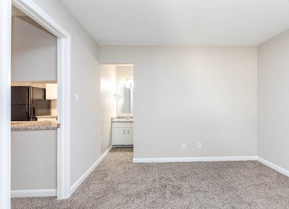 an empty living room with carpet and a kitchen