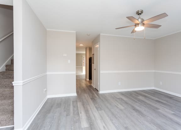 an empty living room with white walls and a ceiling fan
