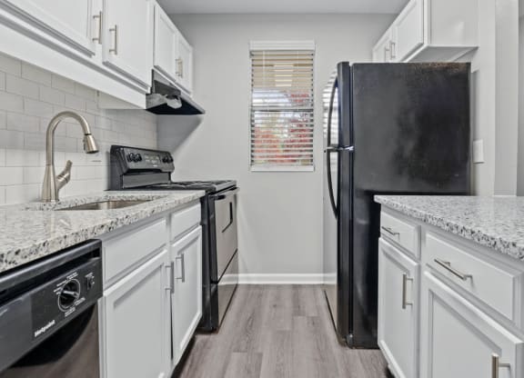 a kitchen with white cabinets and a black refrigerator