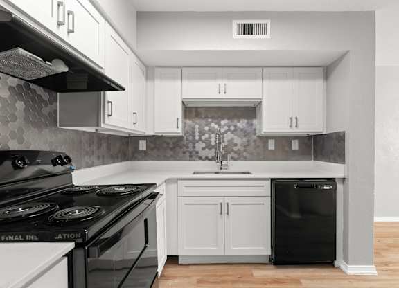 A kitchen with a black stove top oven and white cabinets.at The Sidney, Sherman, 75090